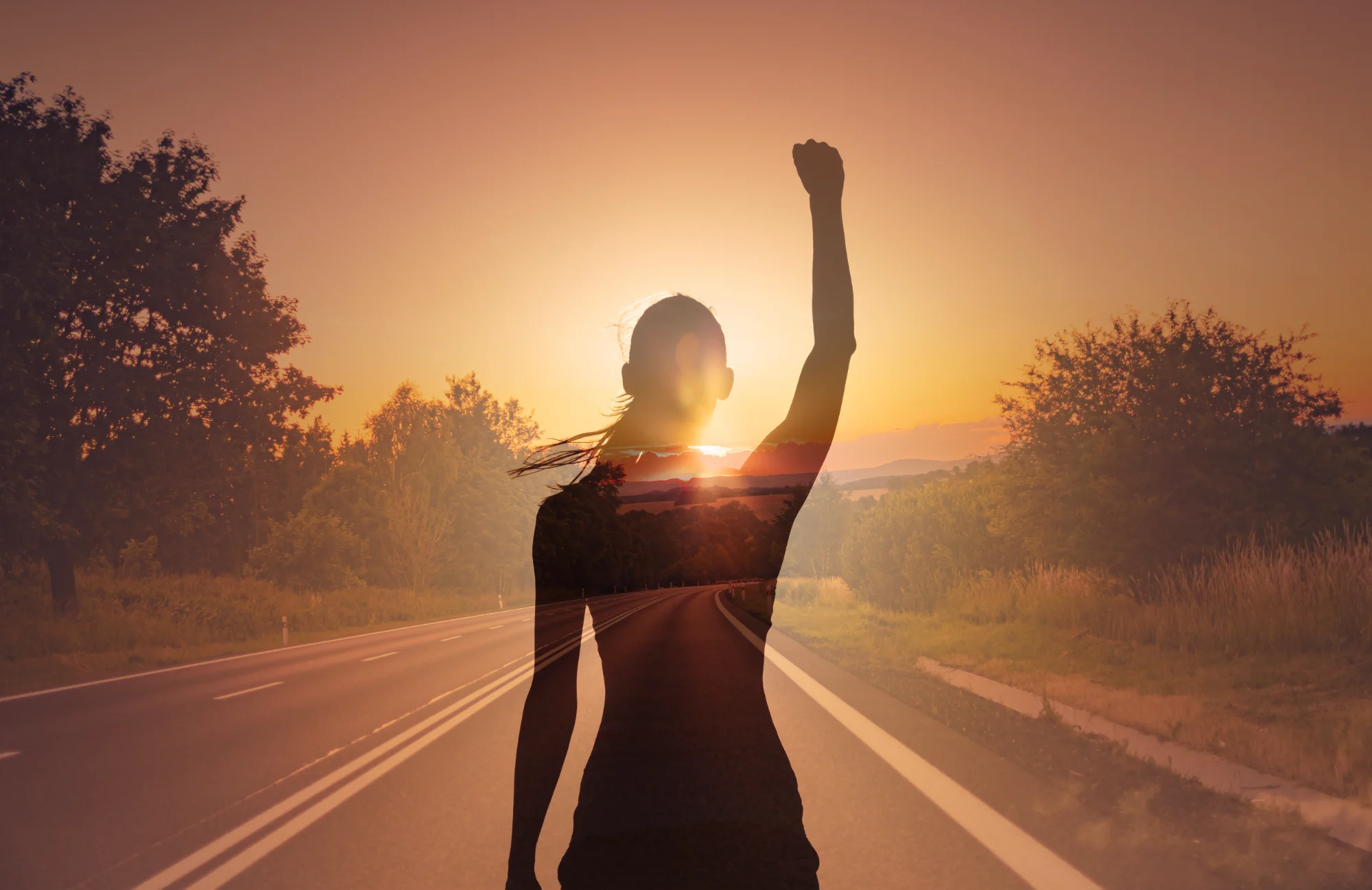 Woman with raised fist at sunrise - empowerment
